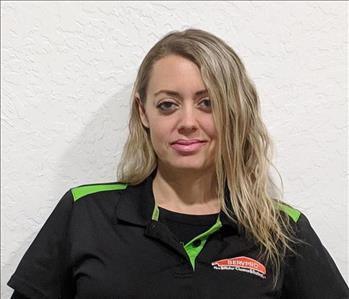 Female employee standing in front of brown background, smiling